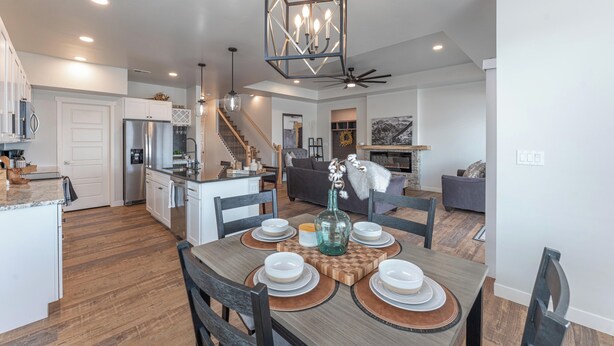 A modern kitchen with white cabinets, a stainless steel refrigerator, and a dining area with a wooden table set for four. - Modern cozy 4-bedroom house in pleasant Grand Junction (Grand Junction)
