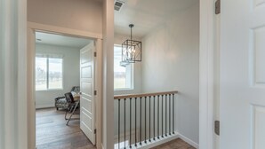 A hallway with a wooden floor, a white door, and a hanging light fixture. - Modern cozy 4-bedroom house in pleasant Grand Junction (Grand Junction)