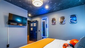 A hotel room with a bed, a TV, a door, and a wall with a starry ceiling. - *NEW* Movie-themed, Speakeasy, Theatre, Games, HotTub, Pets (McGaheysville)