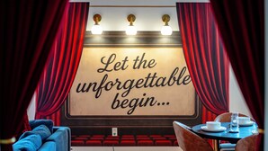 A theater with red curtains, a sign that reads "Let the unforgettable begin...", and a table with plates and a glass. - *NEW* Movie-themed, Speakeasy, Theatre, Games, HotTub, Pets (McGaheysville)