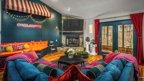 A cozy living room with a sofa, a fireplace, and a TV mounted on the wall. - *NEW* Movie-themed, Speakeasy, Theatre, Games, HotTub, Pets (McGaheysville)