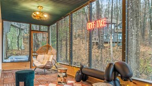 A modern interior with large windows, a wicker chair, a black lounge chair, and a neon sign reading "RUFF TAKE". - *NEW* Movie-themed, Speakeasy, Theatre, Games, HotTub, Pets (McGaheysville)
