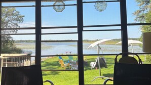 Ett rum med stora fönster med utsikt över en sjö, två stolar, ett litet bord och en hängande lampa.