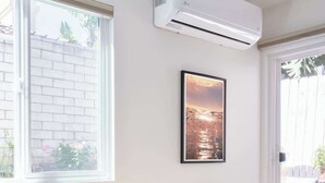Ein Essbereich mit einem runden Tisch, zwei Stühlen und einer an der Wand montierten Klimaanlage.