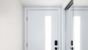Una habitación con una puerta blanca, un ventanal pequeño y un interruptor de luz en la pared.