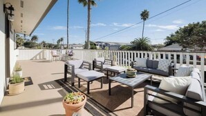 Un balcon aménagé avec du mobilier d’extérieur, notamment des canapés et des fauteuils, ainsi qu’une plante en pot.