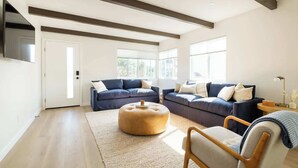 Un salon spacieux avec deux canapés, une table basse en bois et une grande fenêtre qui laisse entrer la lumière naturelle.