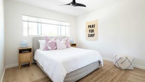 Une chambre à coucher avec un lit, des tables de chevet, une fenêtre et un ventilateur de plafond.