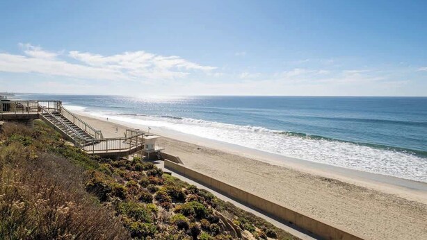 Une plage avec une promenade en béton et des escaliers menant à un poste de surveillance des sauveteurs.