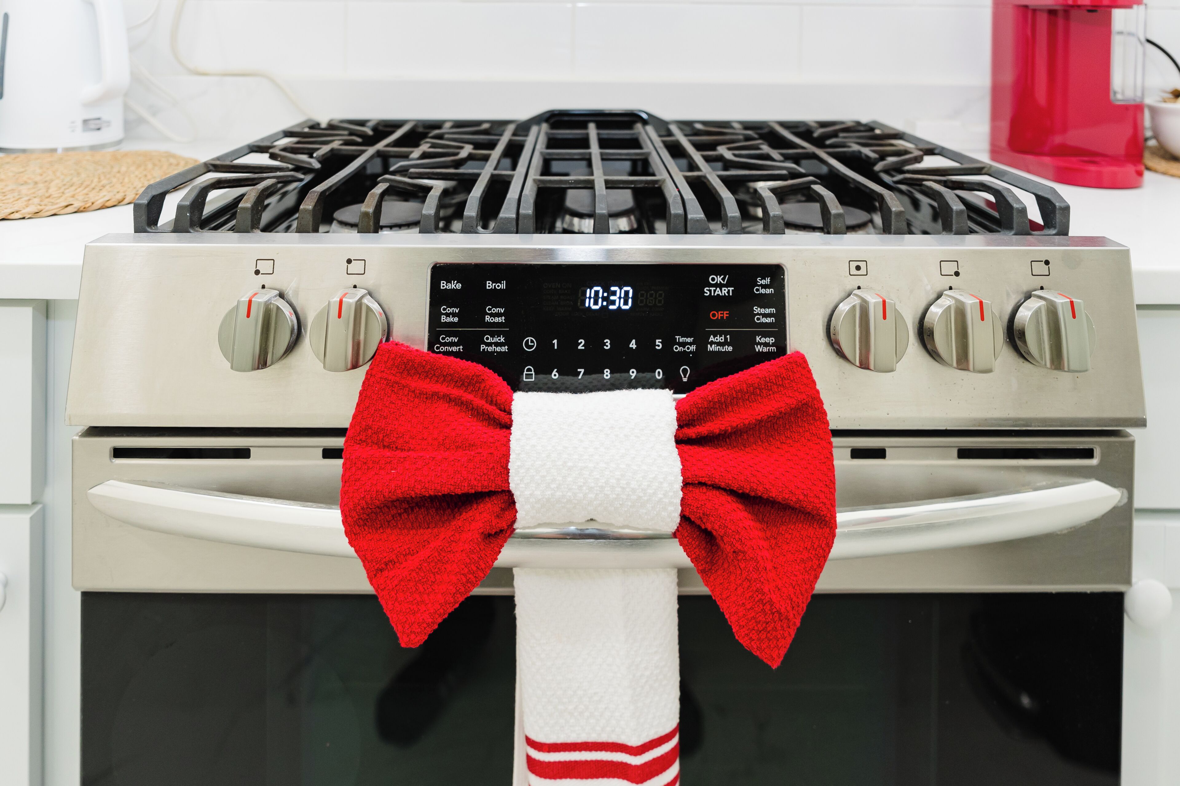 A kitchen with a stove, oven, and a red bow tied around the oven handle.
