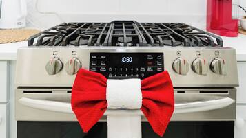 A kitchen with a stove, oven, and a red bow tied around the oven handle.