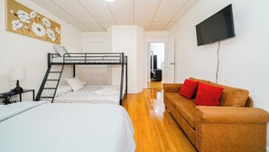 Una habitación con literas, un sofá, un televisor y un cuadro.