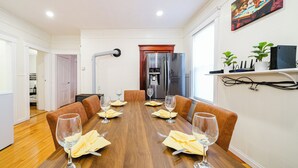 Un comedor con una mesa de madera dispuesta para seis personas, rodeada de sillas de cuero marrón.