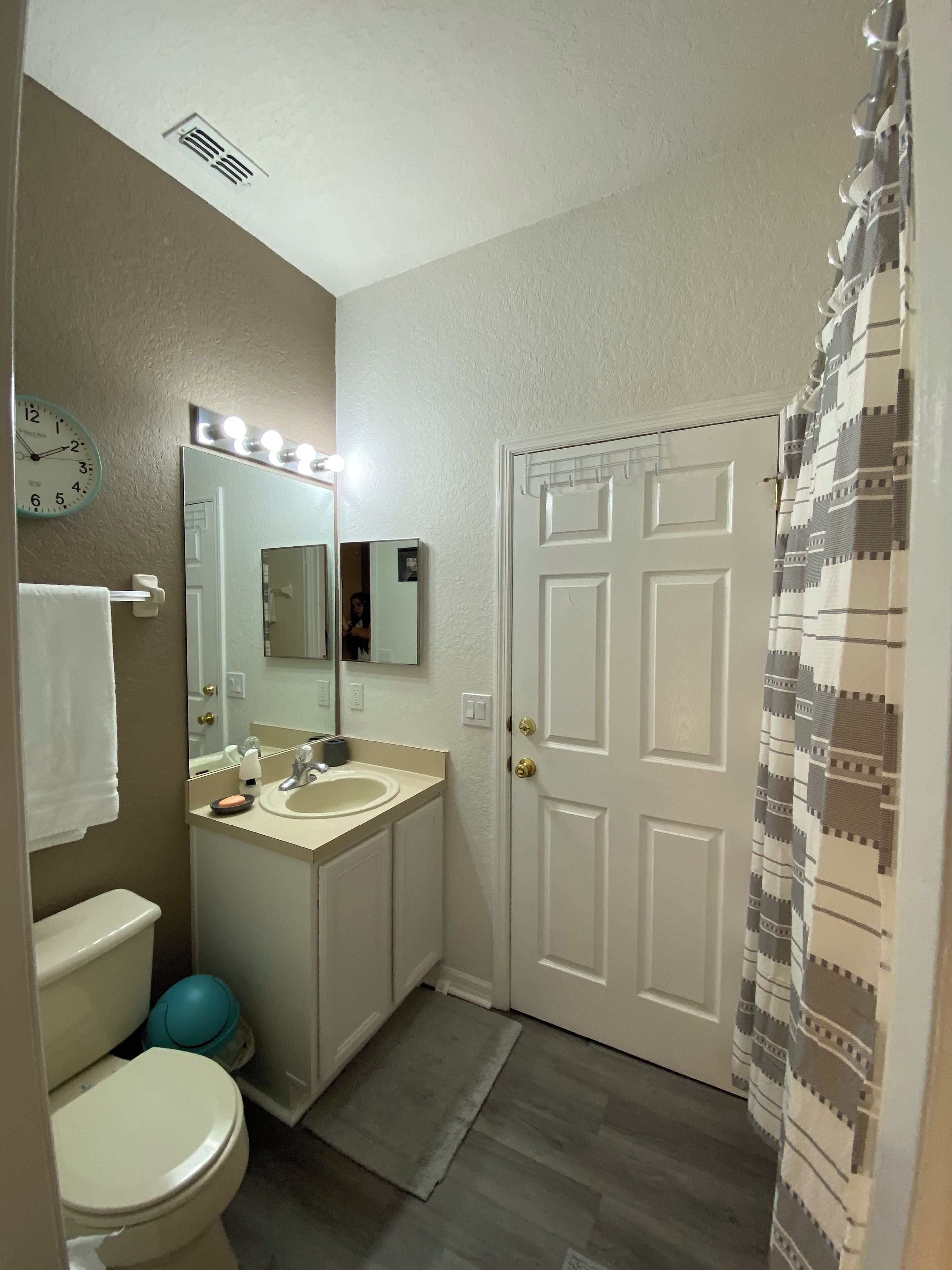 A bathroom with a white toilet, a sink with a mirror above it, and a shower curtain with a geometric pattern.