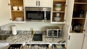 Une cuisine de taille réduite avec des meubles blancs, un four à micro-ondes, un grille-pain et une cuisinière.