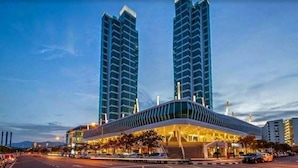 A modern hotel with a curved roof and two tall buildings in the background. - 2BR Maritime Suite Duplex George Town Seaview (George Town)