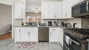 A modern kitchen with white cabinetry, stainless steel appliances, and a central island. - Suburban Retreat Central to Dallas, Plano & Frisco (Dallas)