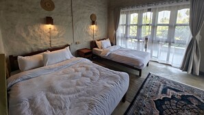 Una habitación con dos camas, un ventilador de techo y un amplio ventanal con cortinas.