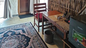Una habitación con una mesa de madera, una silla, un muro tejido, una puerta y un tapete estampado.