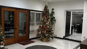 Un interno moderno con un albero di Natale, una porta in legno e un pavimento in marmo.