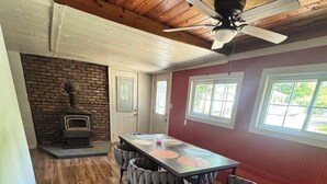 A dining area with a wooden table and chairs, a brick wall, and a ceiling fan. - Perfect and Spacious Hudson Valley Escape! (Cornwall)