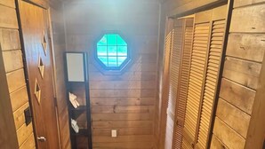 A narrow hallway with wooden walls and a wooden floor. There is a window with a geometric design at the end of the hallway. - Perfect and Spacious Hudson Valley Escape! (Cornwall)