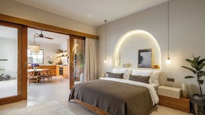 Quarto moderno com cama grande, área de refeições e cozinha visíveis através de uma porta deslizante aberta.