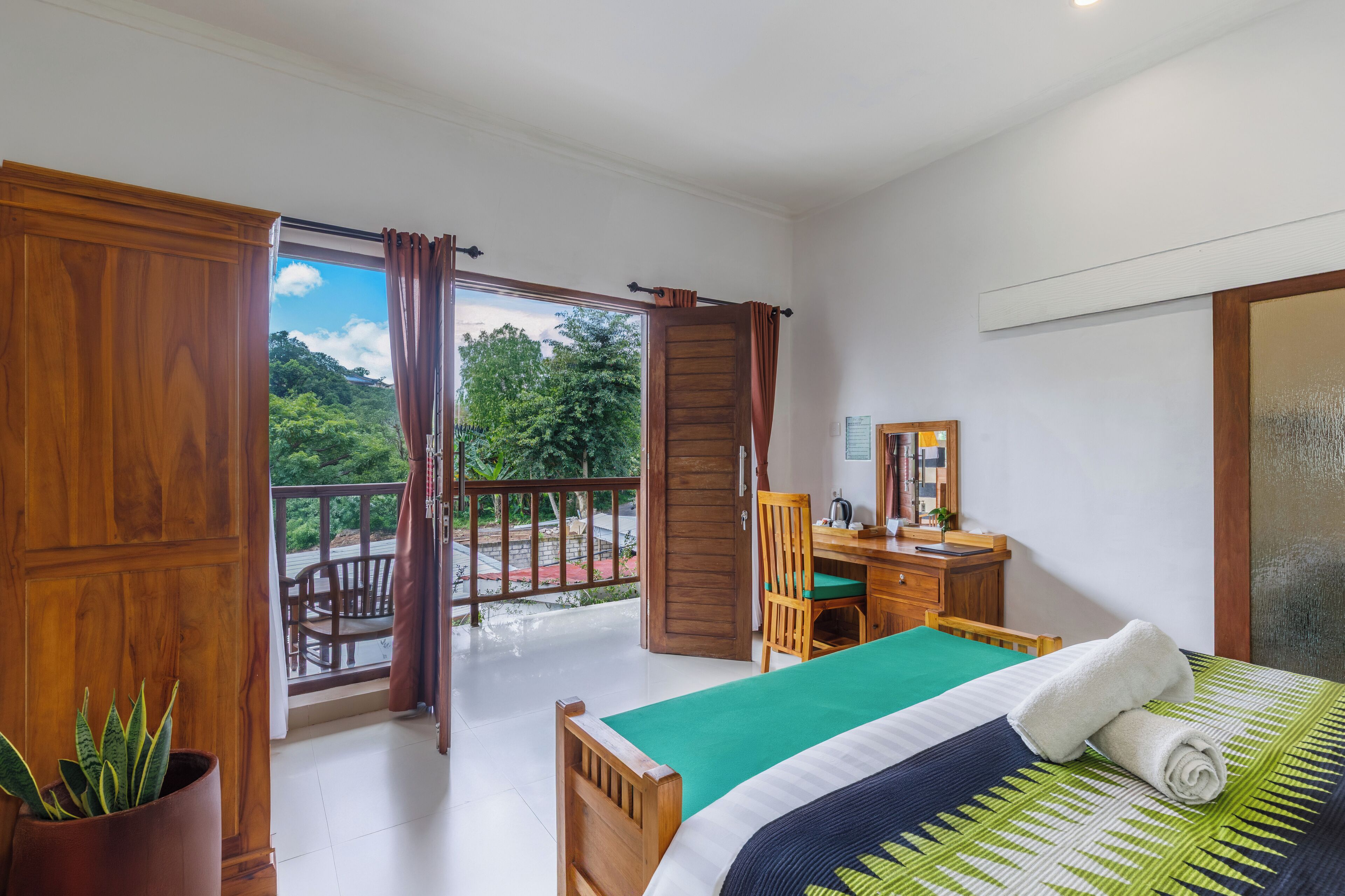 Quarto com cama, escrivaninha, cadeira e planta em vaso.