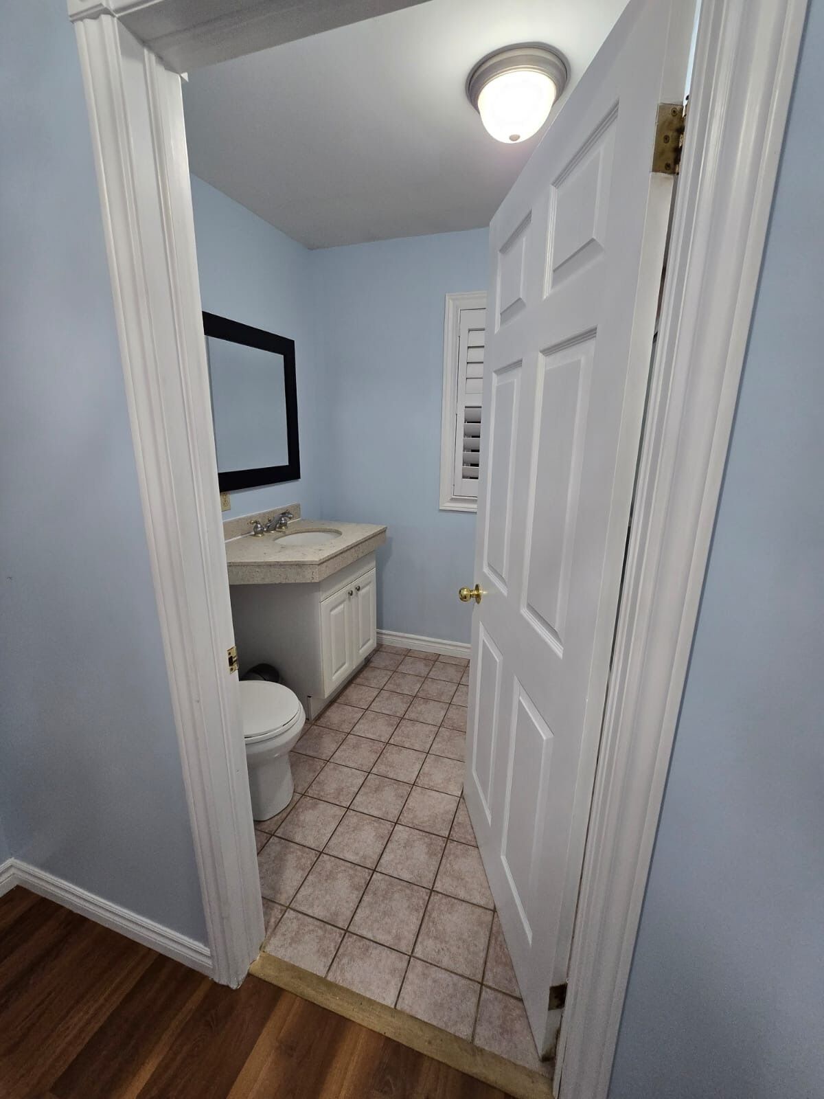 A bathroom with a toilet, sink, and mirror.