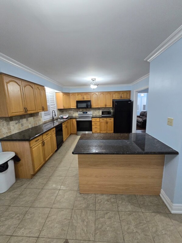 A kitchen with wooden cabinets, a black refrigerator, a microwave, and a stove.