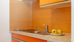 A kitchen with orange cabinets, a stainless steel sink, and a plate with two apples.