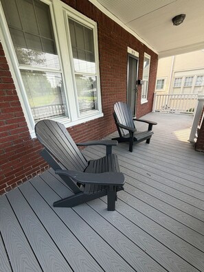 A covered porch with two Adirondack chairs and a small table. - Walk to Gettysburg Battlefield Charming Brick Stay (Gettysburg)