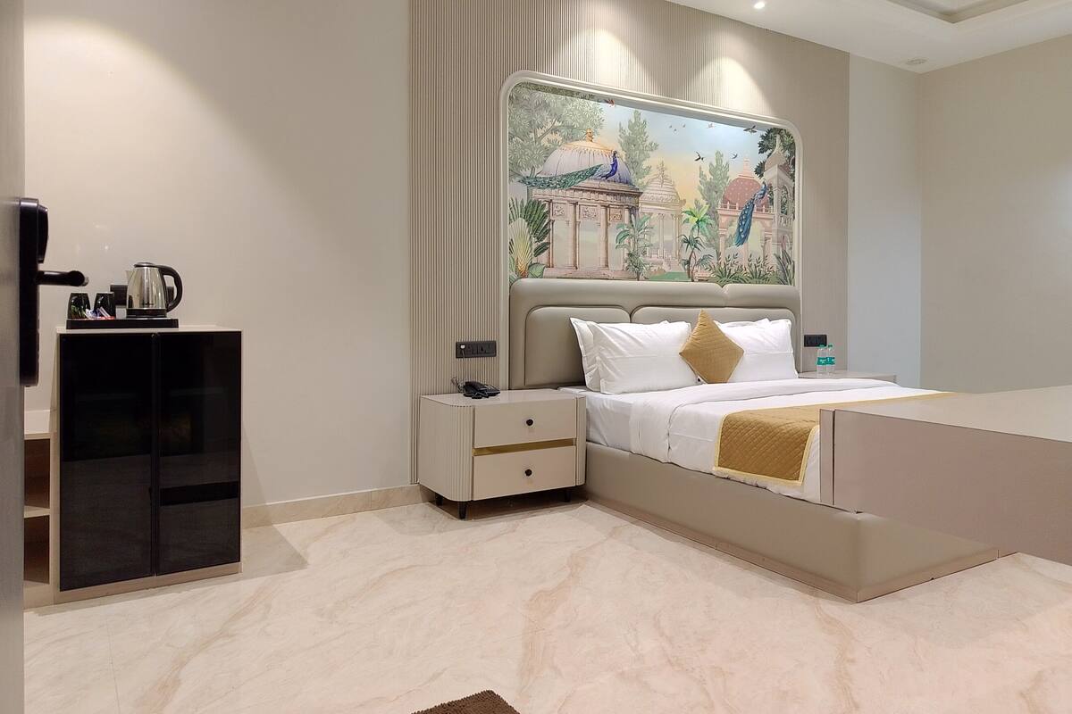 A modern bedroom with a large bed, a nightstand, a coffee maker, and a decorative wall mural.