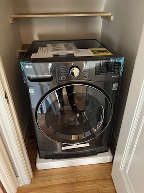 A compact, modern washer and dryer unit with a control panel, a large glass door, and a small shelf above the unit. - Mid-Term Rental - Over 30 Days - Saint Paul near colleges (Saint Paul)