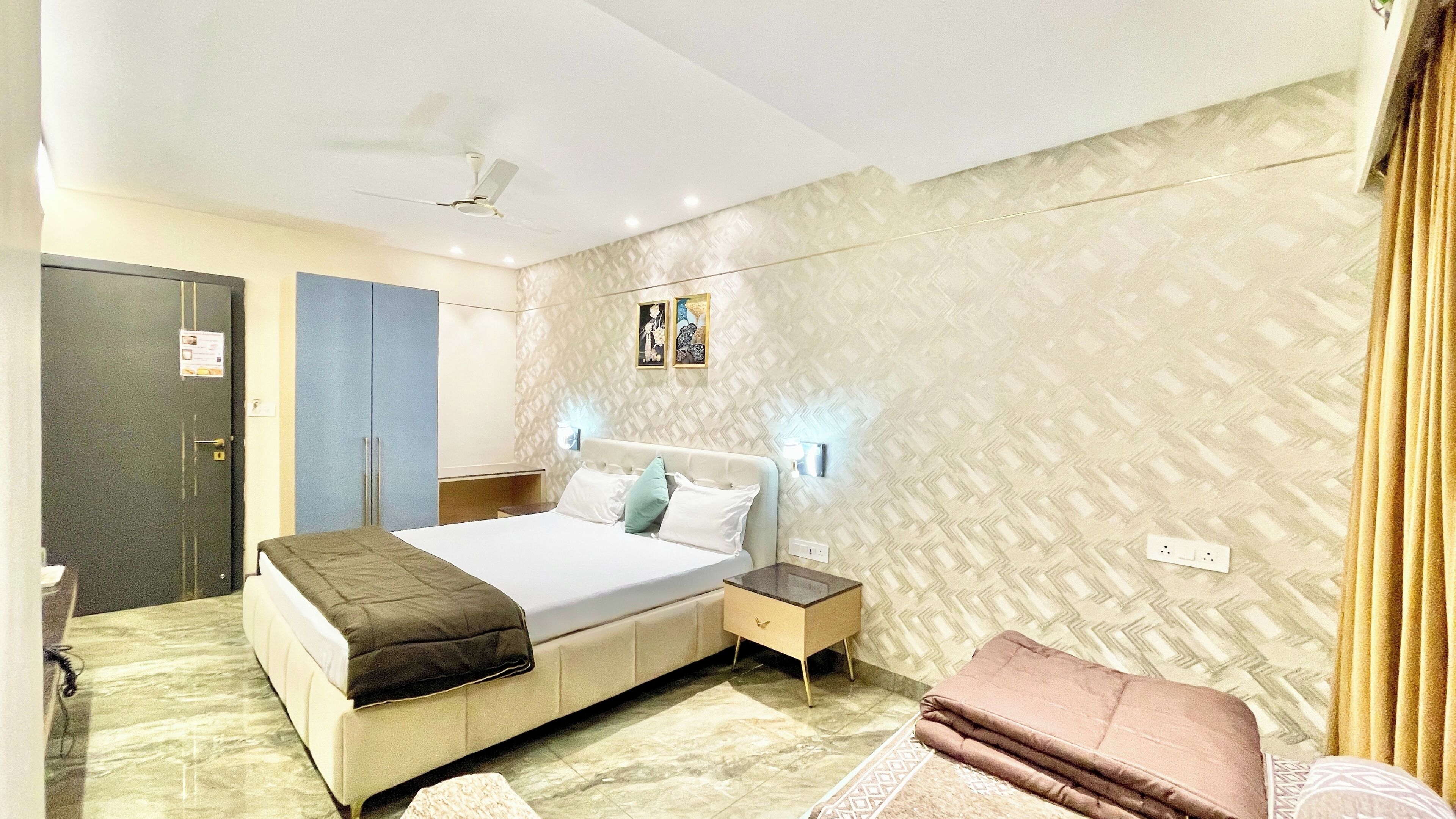 Une chambre d’hôtel avec un lit, une table de chevet et un luminaire fixé au mur.