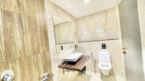 A modern bathroom with a marble vanity, a toilet, and a shower. - Premium Hotel M Shri near Mahakal Temple (Ujjain)