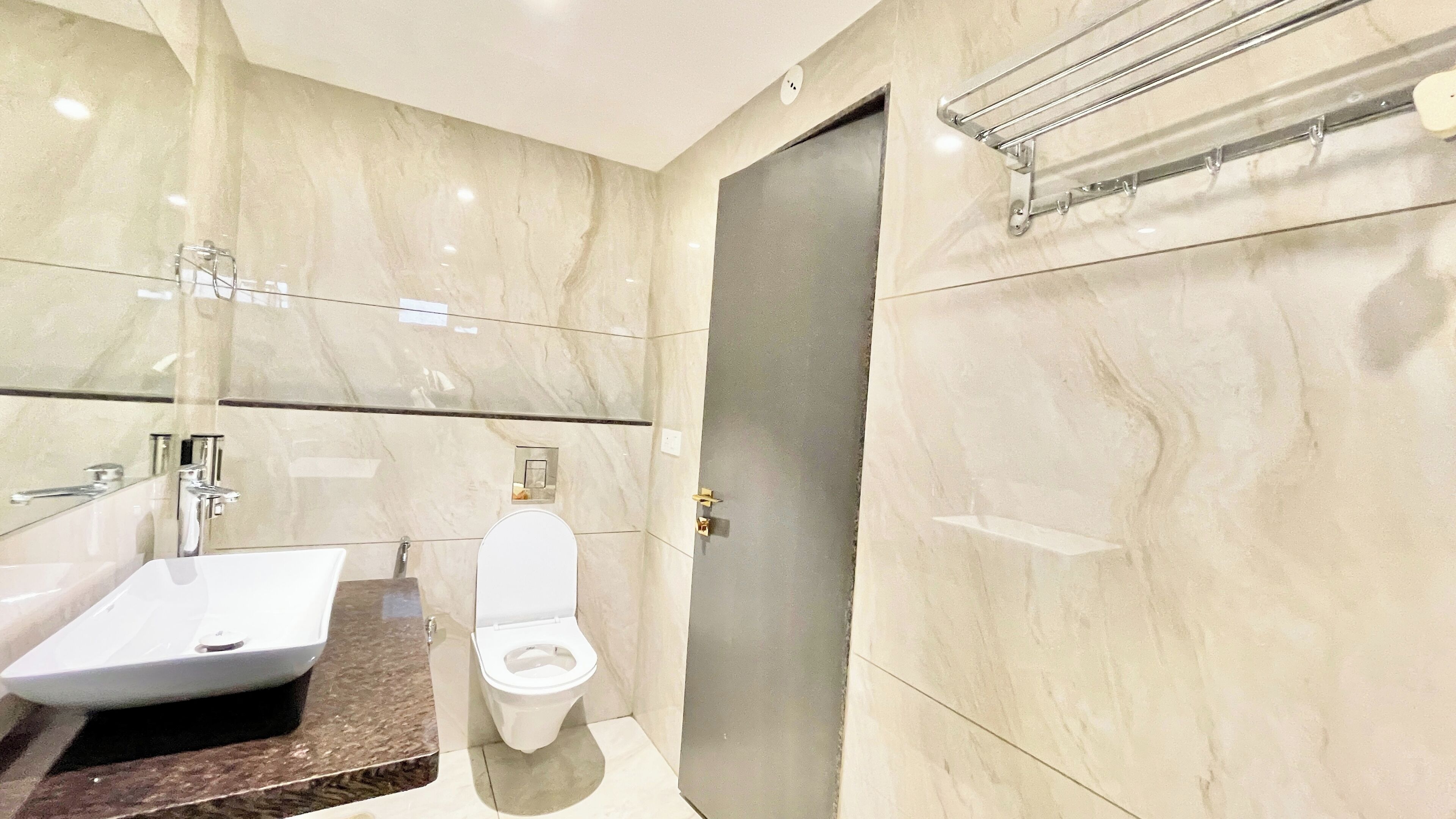 Un baño moderno con lavamanos de mármol, inodoro y zona de ducha.