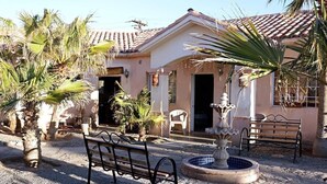 A building with a tiled roof, a fountain, and a bench in the foreground. - Costa del Sol Hotel & Sportfishing (Bahía de los Ángeles)