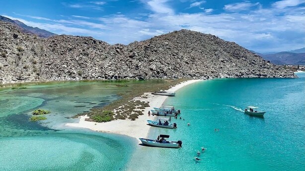 A coastal landscape with clear turquoise waters, rocky terrain, and boats anchored near the shore. - Costa del Sol Hotel & Sportfishing (Bahía de los Ángeles)