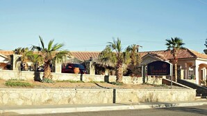 A hotel named Casa del Sol with a stone facade, palm trees, and a tiled roof. - Costa del Sol Hotel & Sportfishing (Bahía de los Ángeles)