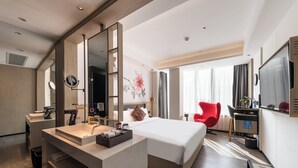 A modern hotel room with a large bed, a vanity with a mirror, a red chair, and a television. - Paco Hotel Canton Tower Pazhou (Guangzhou)