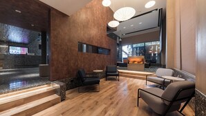 A modern lobby with a wooden floor, seating area, and a reception desk. - Paco Hotel Canton Tower Pazhou (Guangzhou)