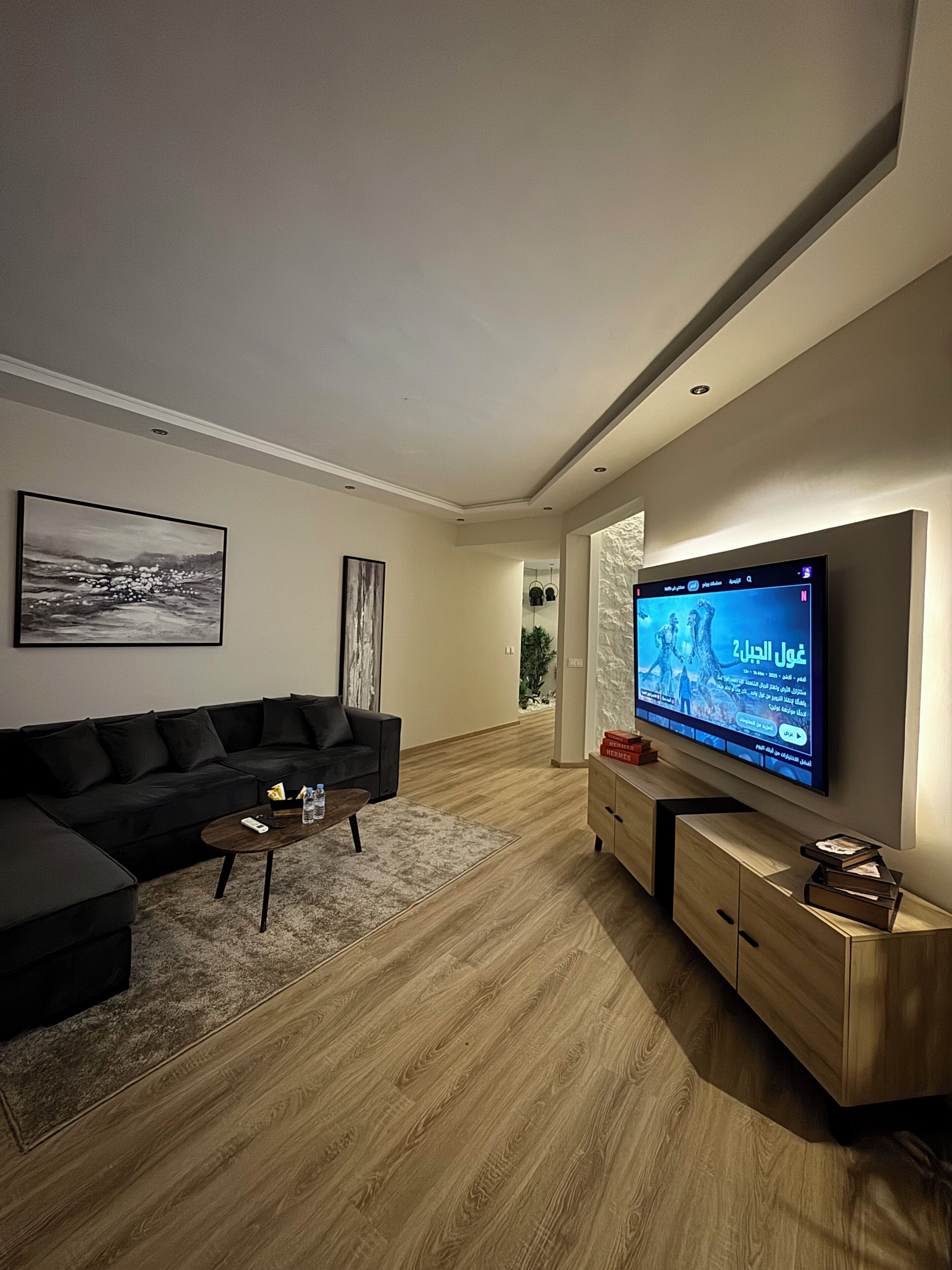 A modern living room with a sectional sofa, a flat-screen TV, and a wooden cabinet.