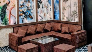 Un salon moderne avec un canapé d’angle, un lustre et des œuvres d’art d écoratives accrochées au mur.