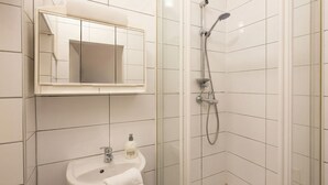 Un bany amb dutxa, un lavabo amb mirall i una tovallola penjada al lavabo.