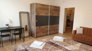 Una habitació amb un llit, un escriptori, dues cadires, un armari i un sofà.