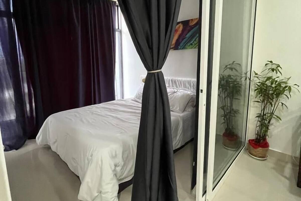 Un dormitorio con cama, puerta corredera de vidrio y una planta en maceta.