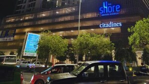 Un edificio de gran altura con señalización iluminada que dice 'The Shore' y 'Citadines'.