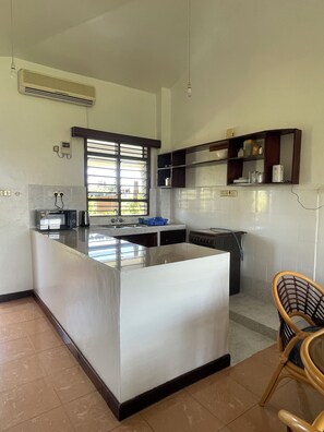 Una cocina moderna con una isla central, horno empotrado y ventana con persianas.