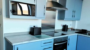Une cuisine moderne avec des meubles de couleur bleu clair, une hotte de cuisinière en acier inoxydable, un four à micro-ondes encastré et un four noir.